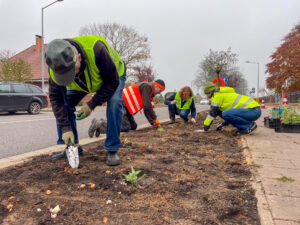 Eine Gruppe Menschen mit Warnwesten setzt Blumenzwiebeln fürs Stadtgrün