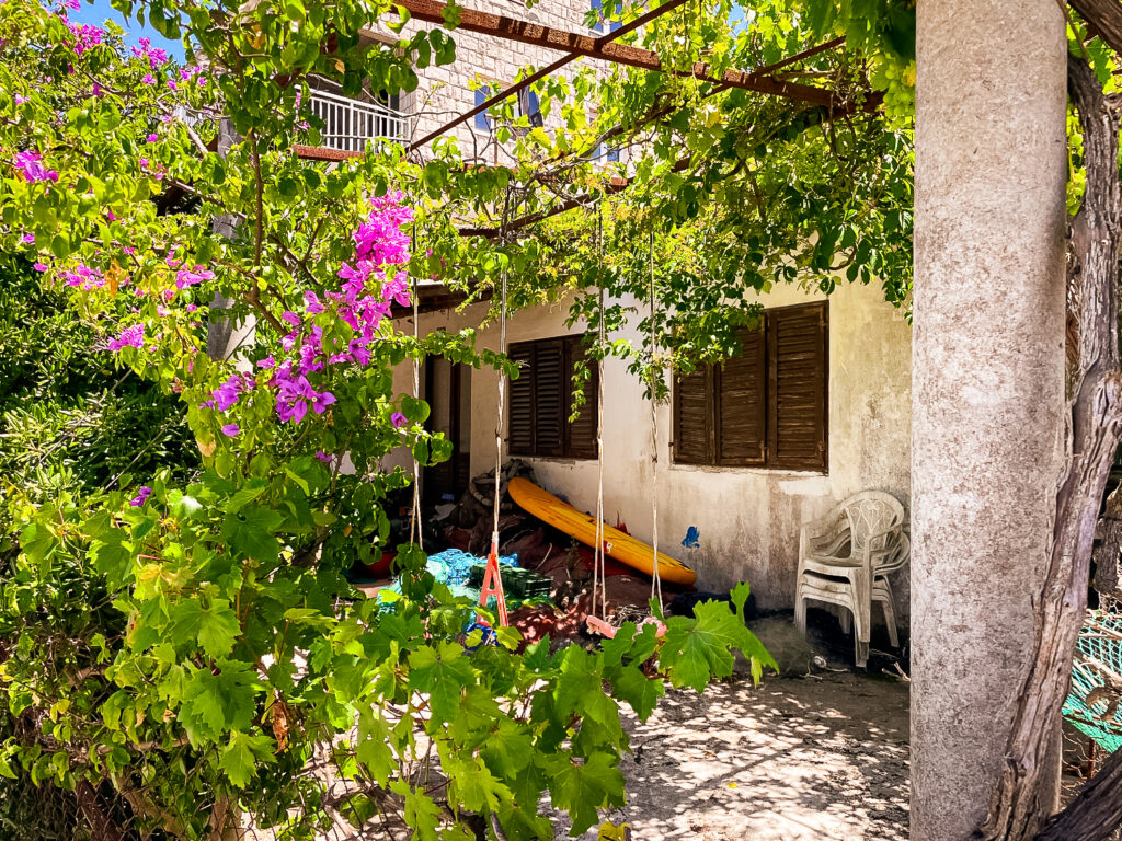 Berankte Pergola über einem Sitzplatz mit Schaukeln an einer Straße in Kroatien